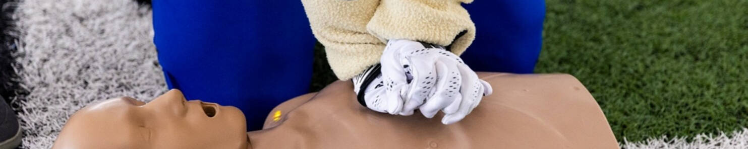 Louie the Laker performs CPR on a manikin